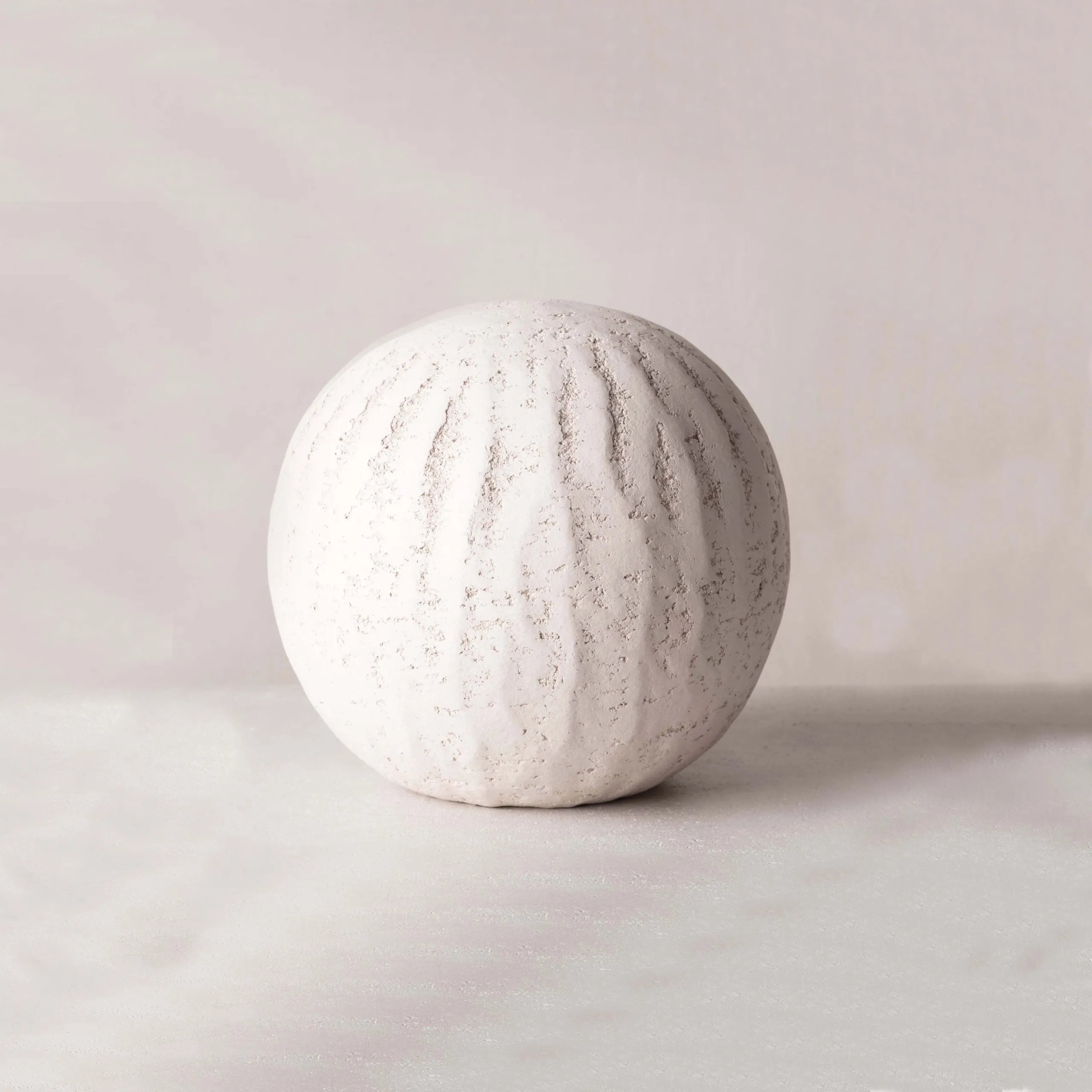 sphère en grès ivoire, dont la texture organique évoque la pureté, la force de la nature, façonnée à la main, révélant la beauté sobre et authentique du matériau brut